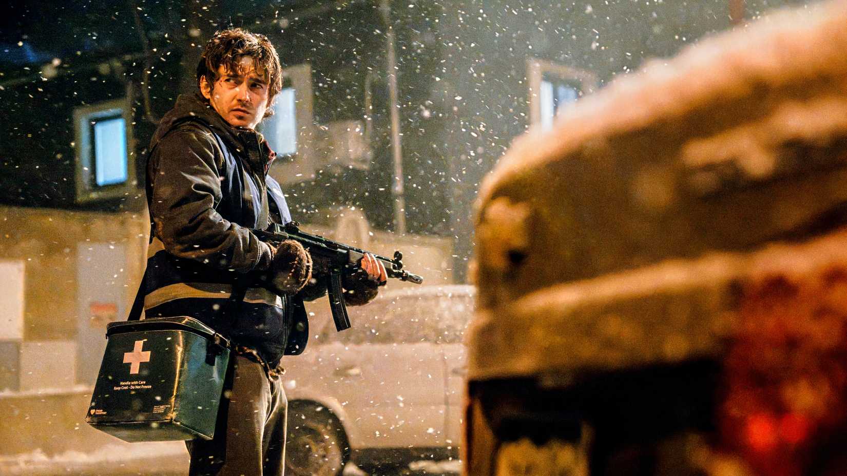 Bryan (Austin Abrams) holds a medical package and machine gun in Resident Evil (2026)