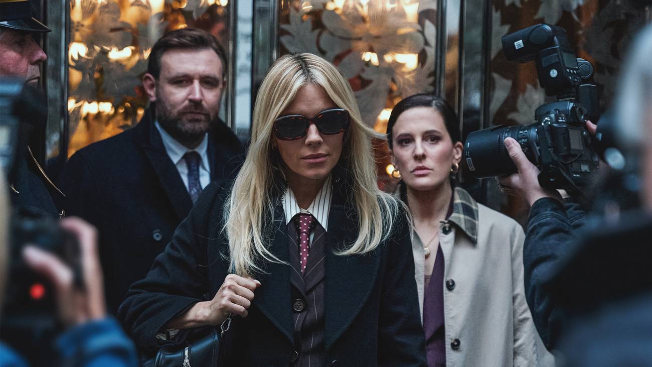 Carla walks in between photographers with her lawyers behind her in HBO's War