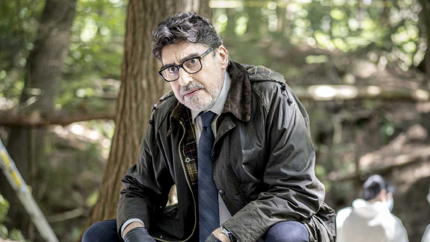 Chief Inspector Armond Gamache crouches down in the forest in Three Pines