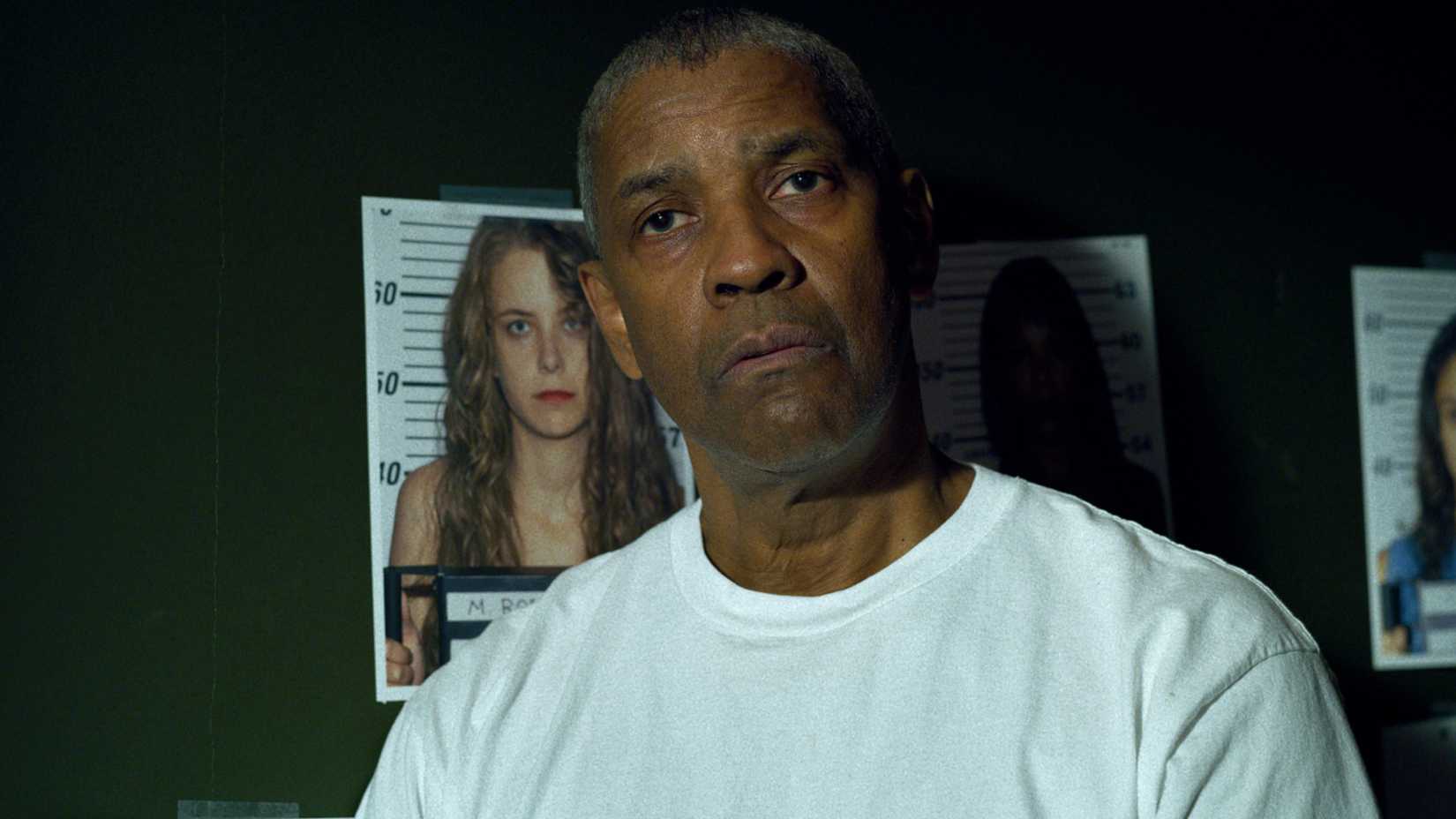 Denzel Washington with mugshots of girls behind him in The Little Things