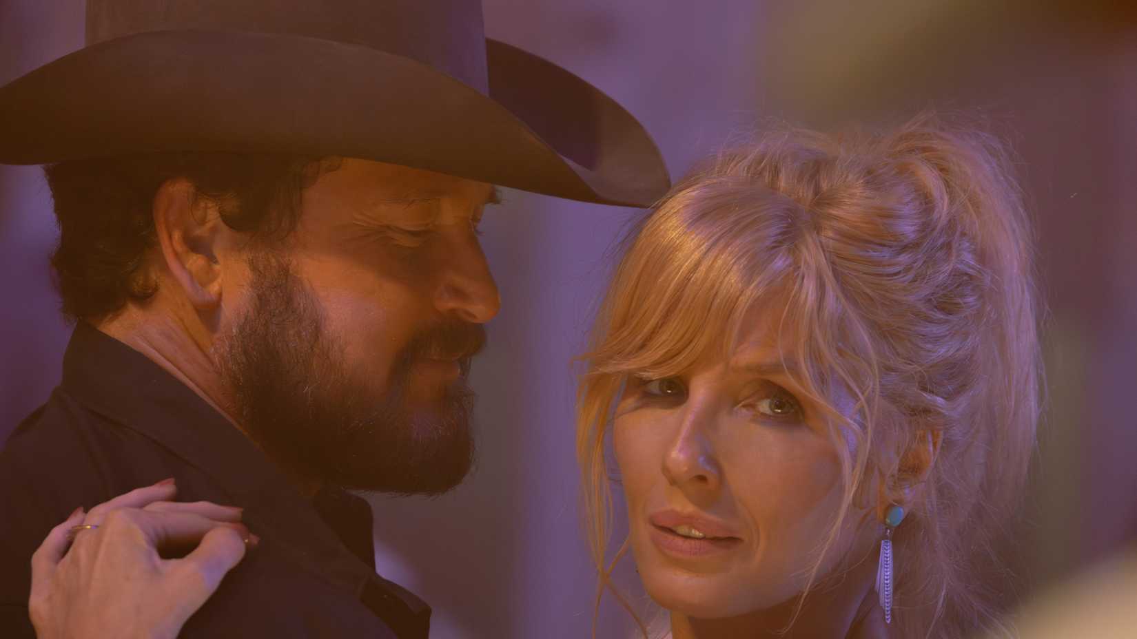 Cole Hauser and Kelly Reilly dancing in Dutton Ranch. Reilly is looking towards the camera.
