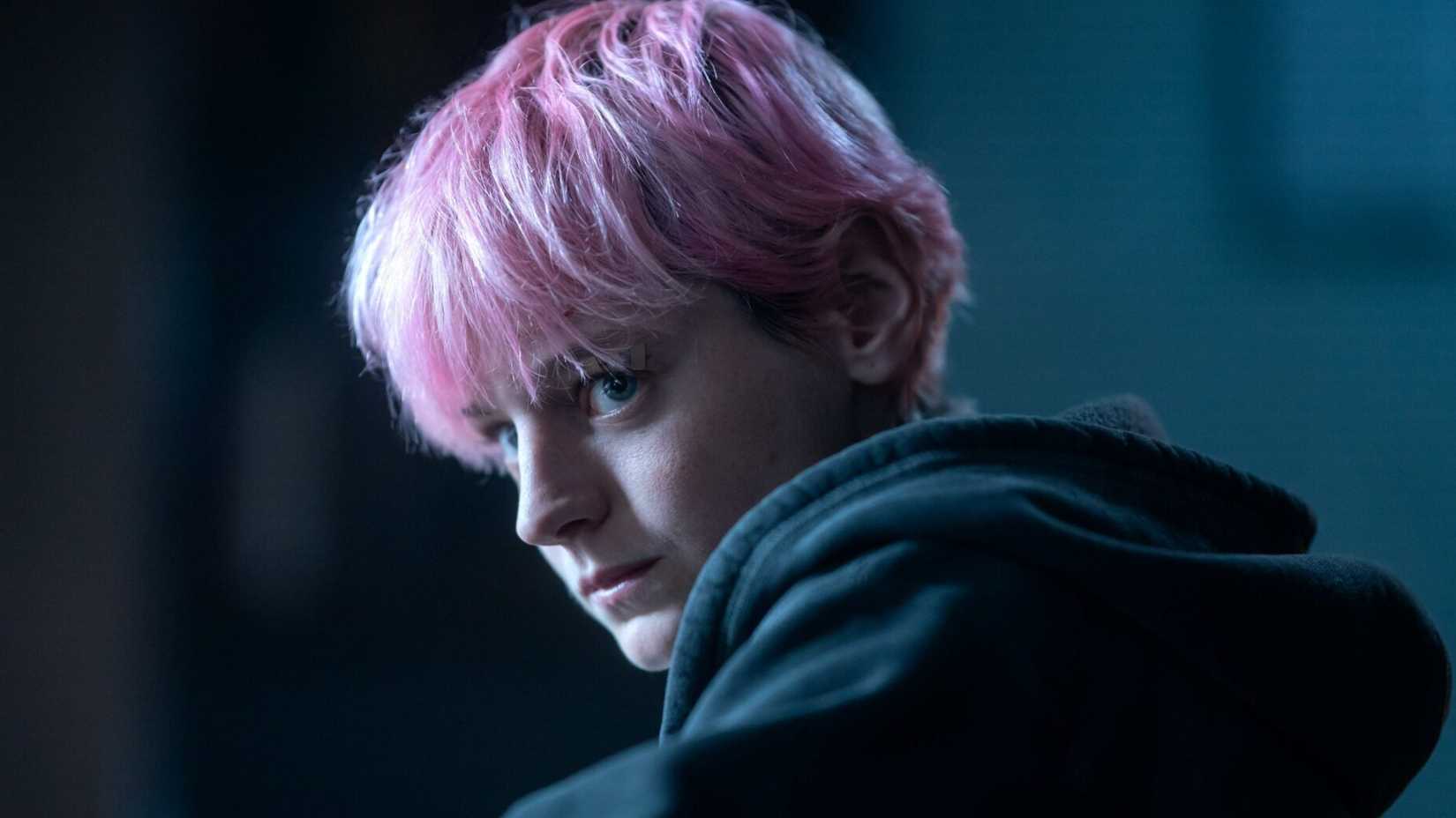 Darby (Emma Corrin) looking over her shoulder in A Murder at the End of the World