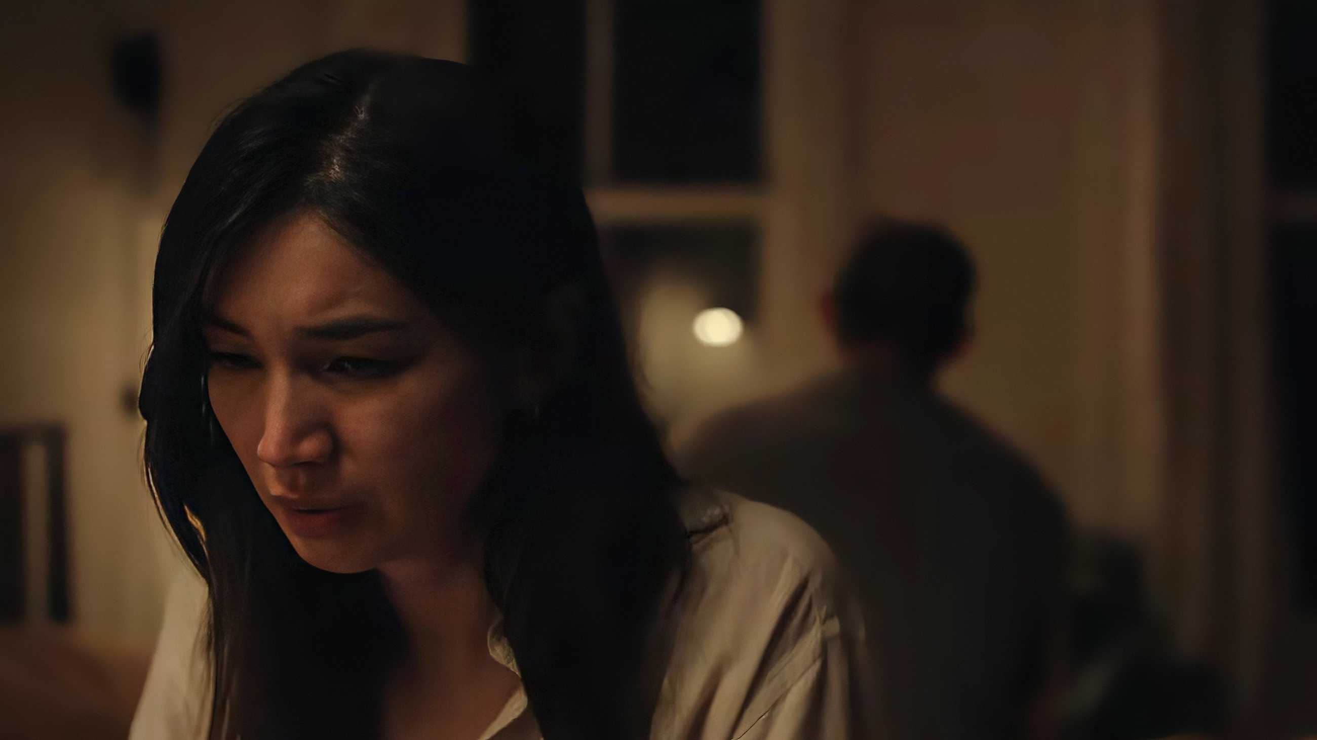 Gemma Chan sitting on a bed with a horrified expression in Josephine