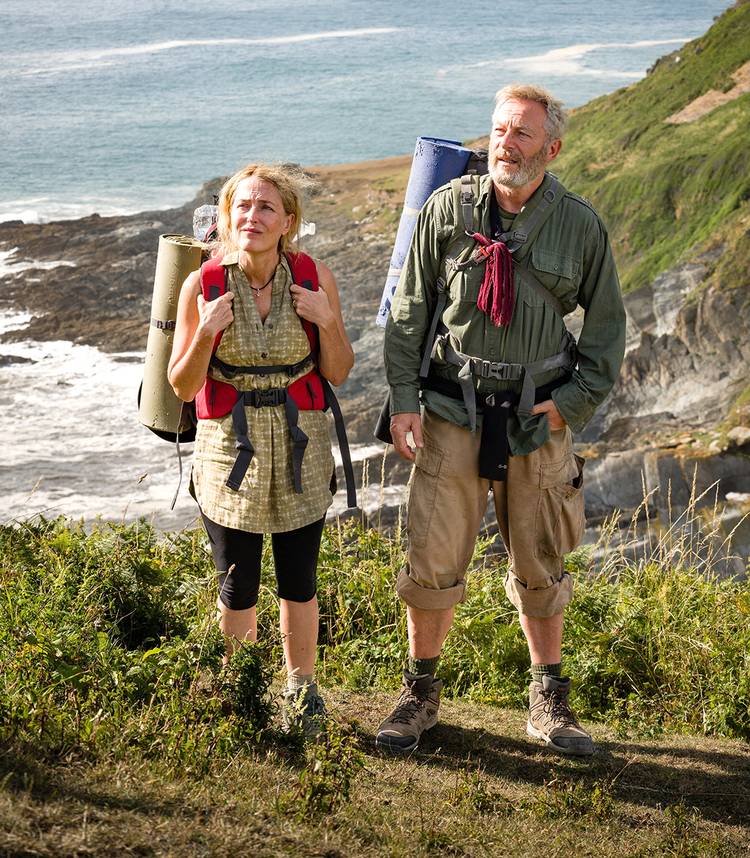 Gillian Anderson's Raynor and Jason Isaacs' Moth standing on a cliffside in The Salt Path