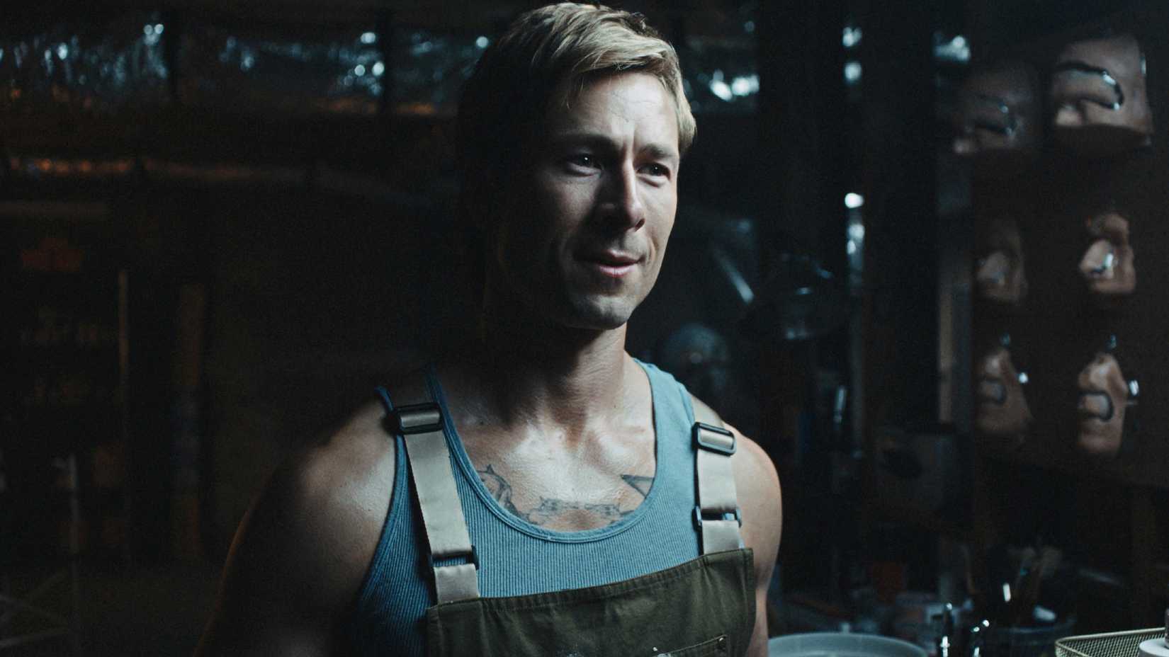 Glen Powell in Chad Powers season 2 in a basement with masks around him on the wall