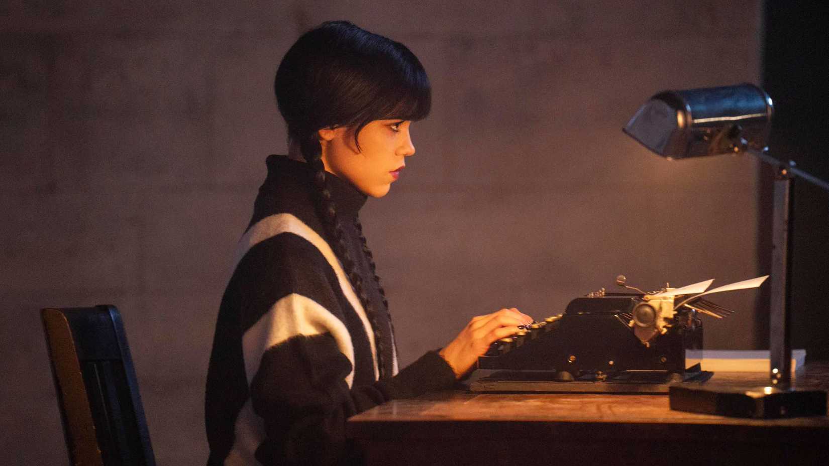 Jenna Ortega as Wednesday Addams typing on her typewriter in Wednesday season 3
