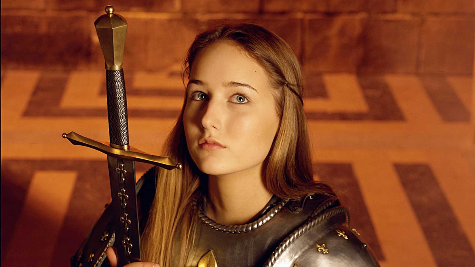 Leelee Sobieski as Joan d'Arc holding a sword and looking up in Joan of Arc.