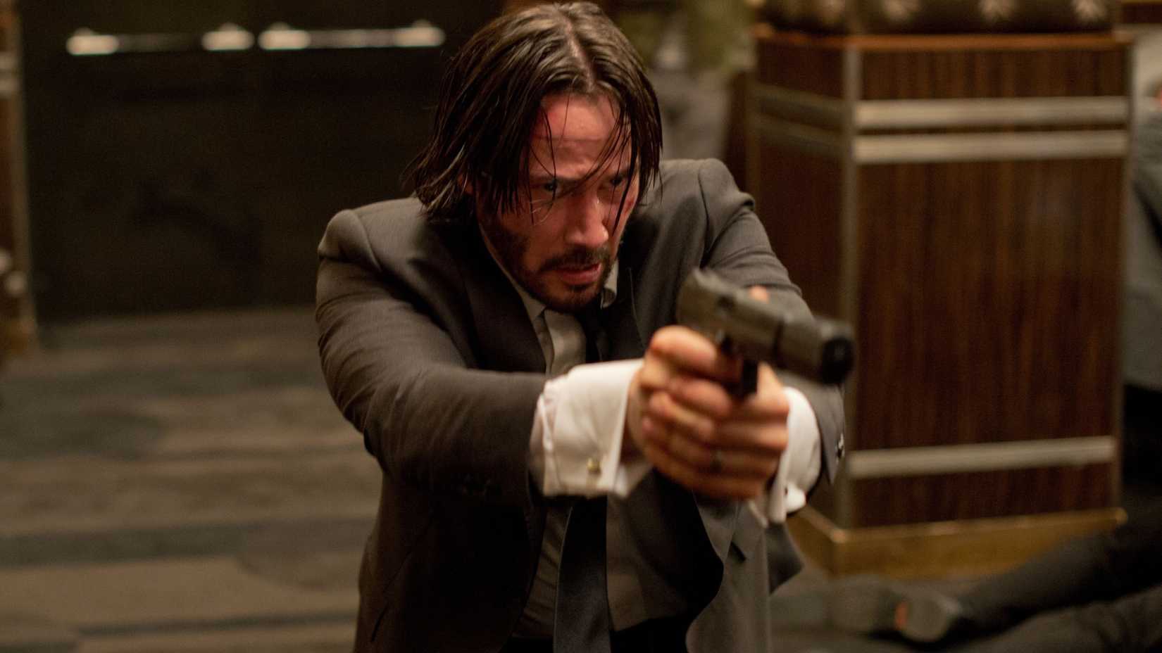John Wick aiming a pistol in a nightclub