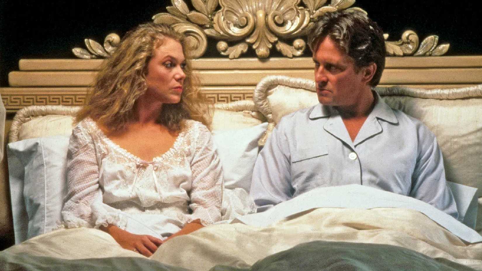 Kathleen Turner and Michael Douglas look at one another in bed in War of the Roses