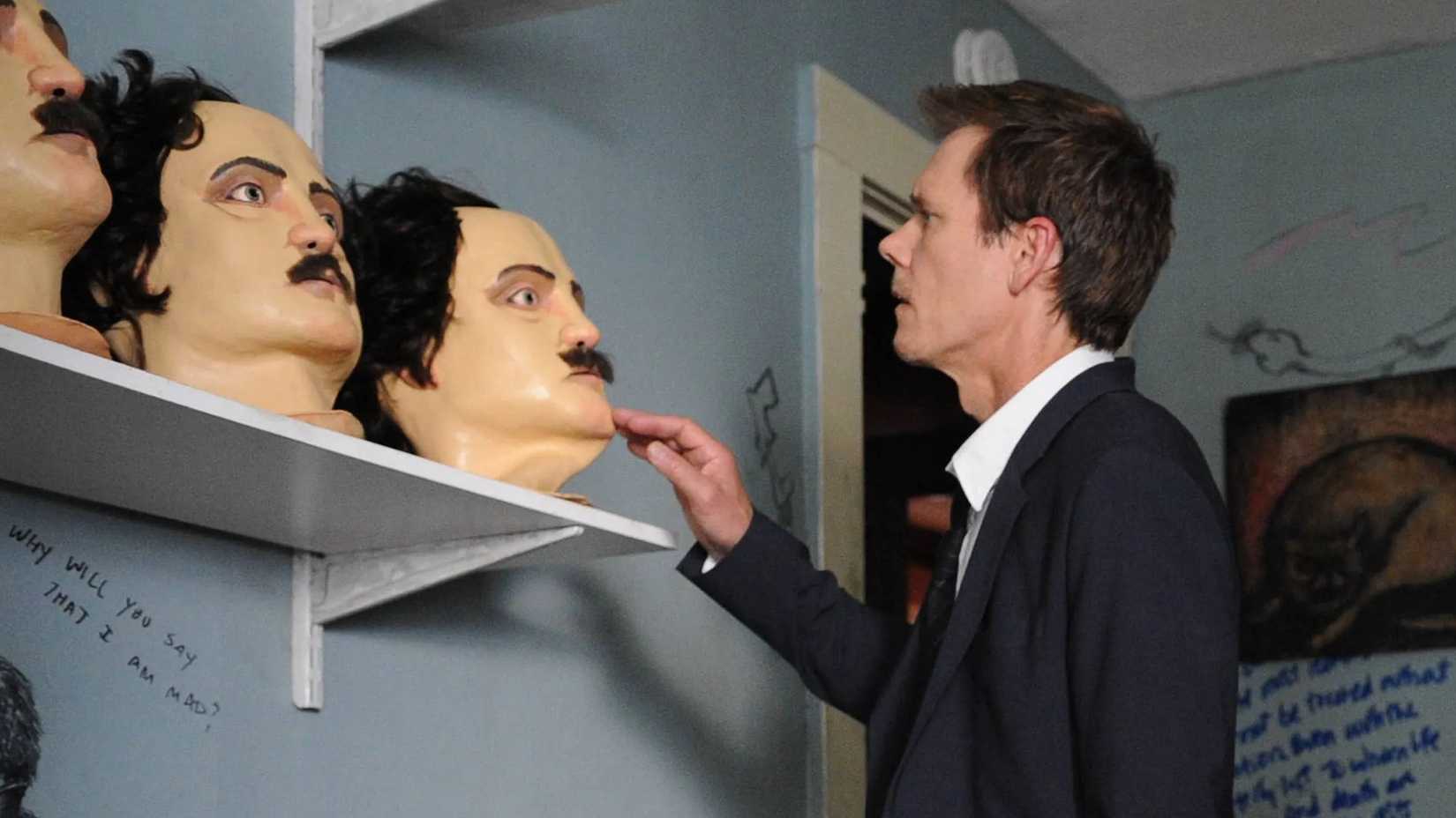 Kevin Bacon examining heads modeled after Edgar Allen Poe in The Following.