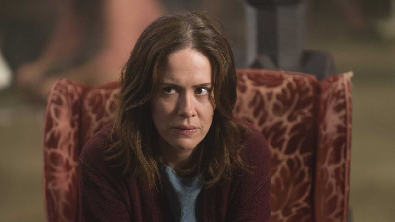 Lana Winters looks upset while sitting in a chair in American Horror Story season 2