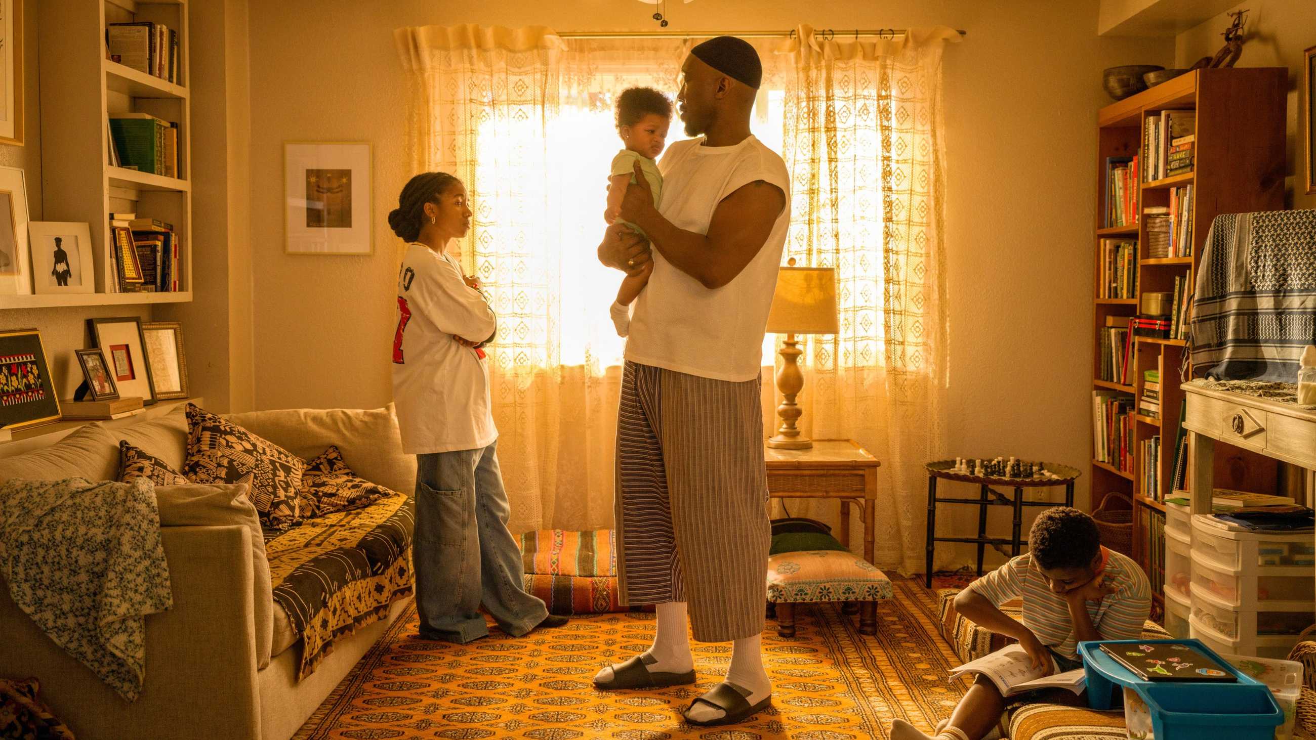 Latif and his three children in a yellow-lit living room in Your Mother Your Mother Your Mother
