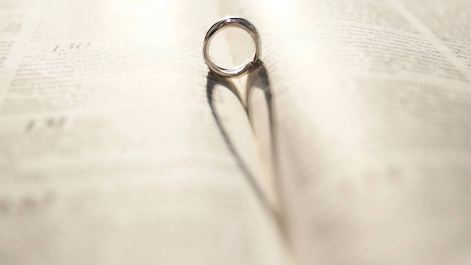 Photo of a wedding ring nestled into the binding of a book.