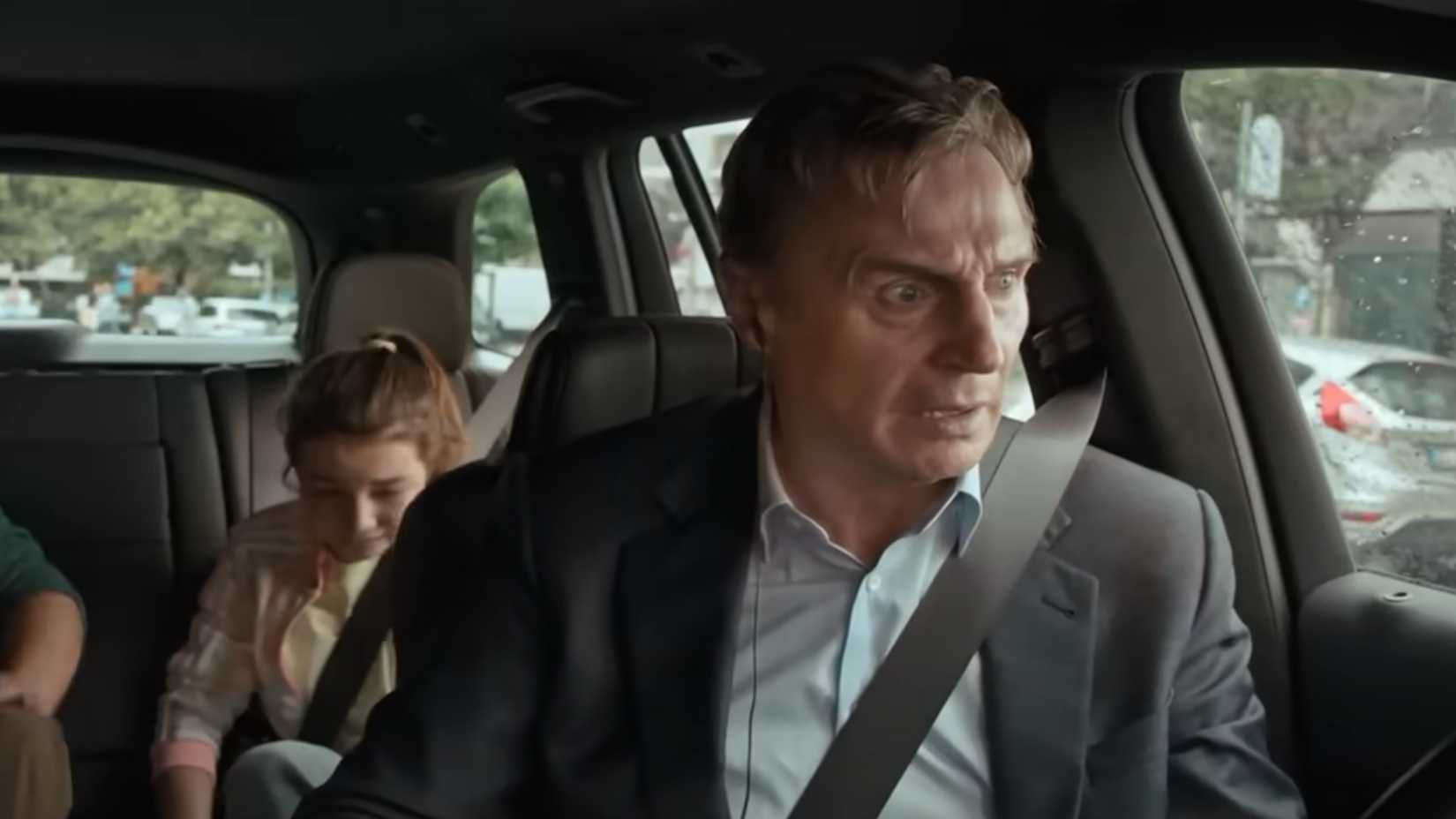 liam neeson looking shocked in the drivers seat with kids in the back in Retribution