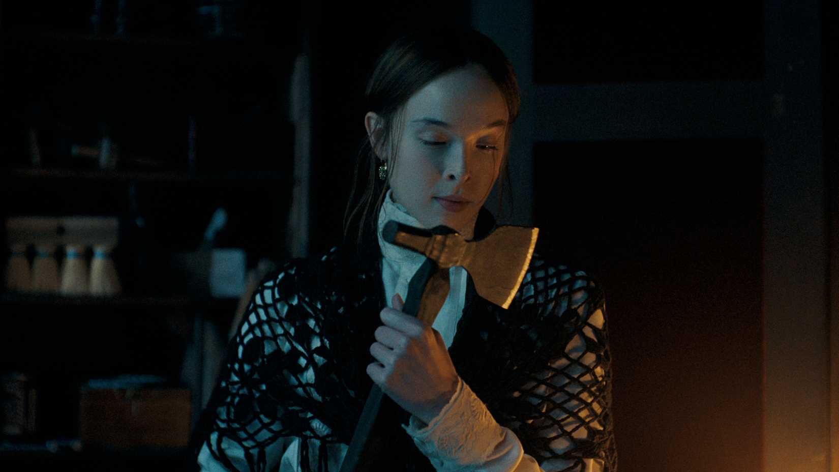 Lizzie Borden looks down at an axe she's holding in Monster: the Lizzie Borden Story