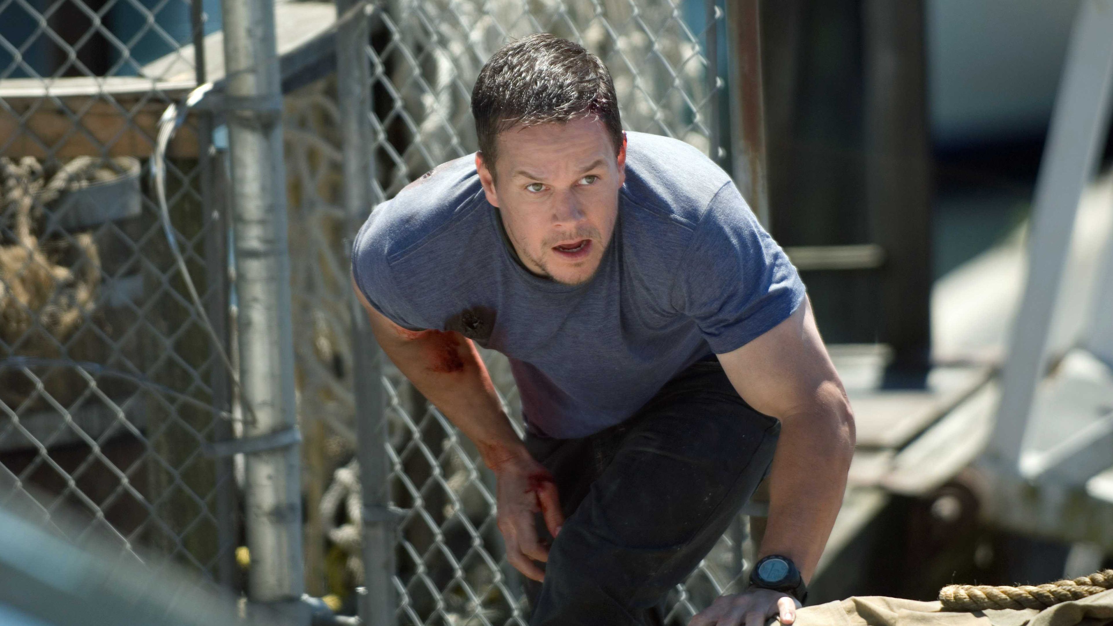 Mark Wahlberg's Bobby Lee Swagger crouching and looking intense with some blood on his shirt in Shooter