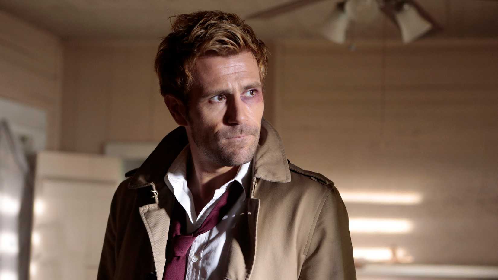 John Constantine, played by Matt Ryan, looks to the side while wearing a red tie and a trench coat in the TV show Constantine
