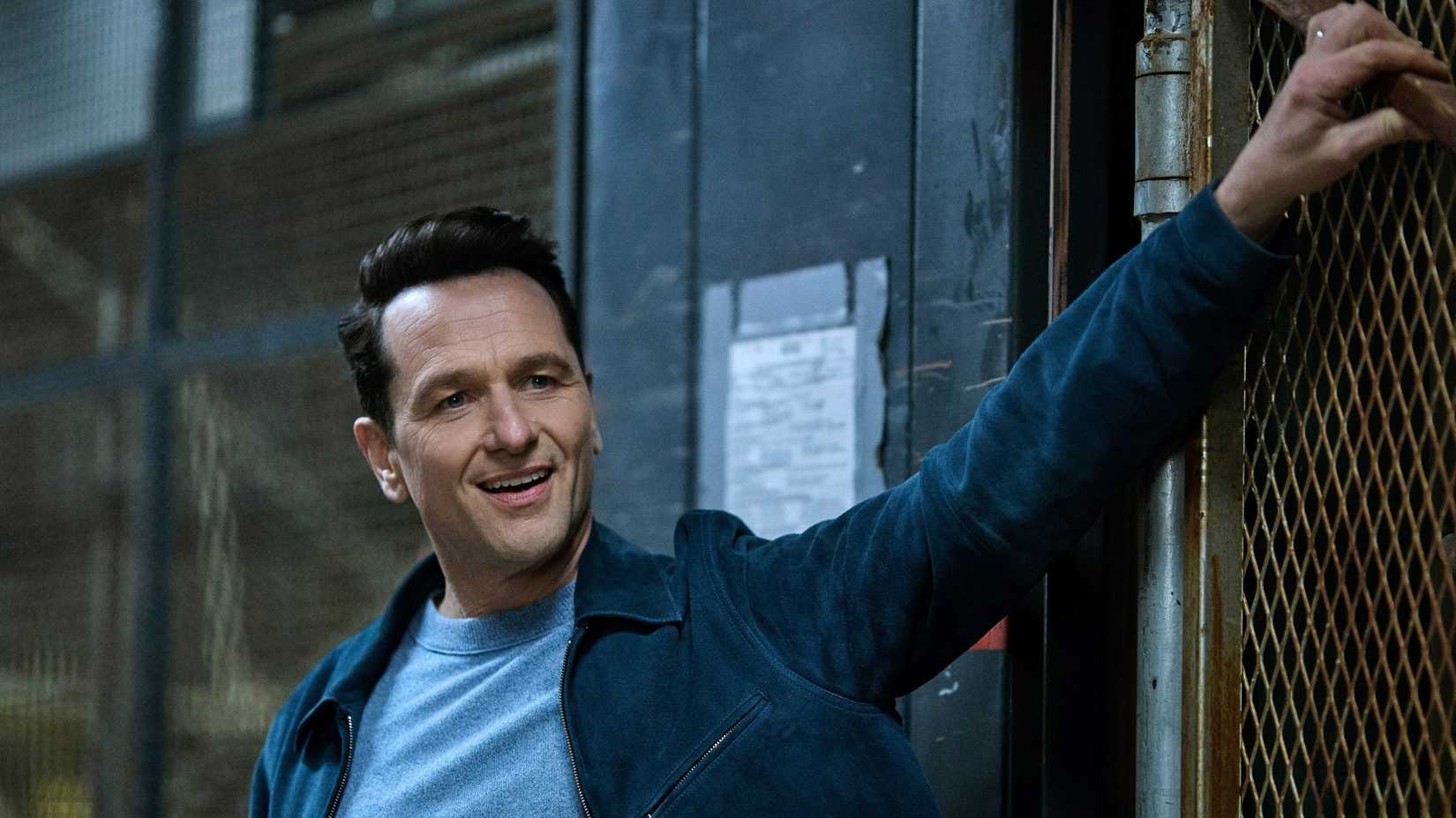 Matthew Rhys as Nile Jarvis putting his hand on a fence and smirking in The Beast in Me