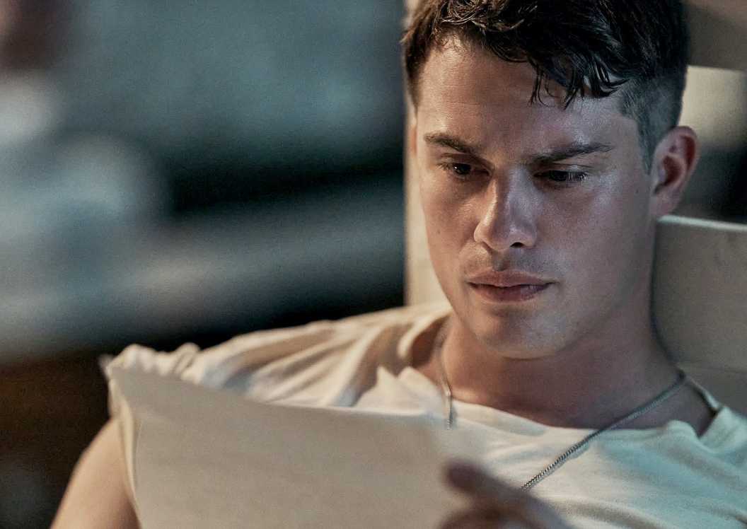 Nicholas Galitzine reading a letter in bed in The Mosquito Bowl