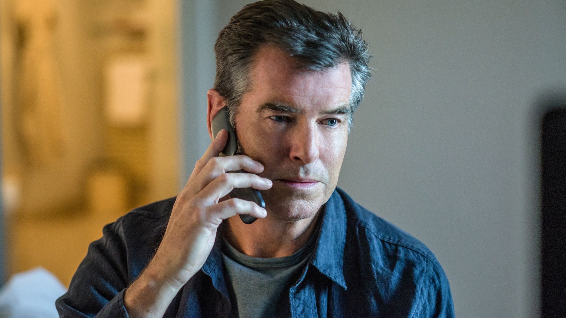 Pierce Brosnan listening to someone on the phone in The November Man