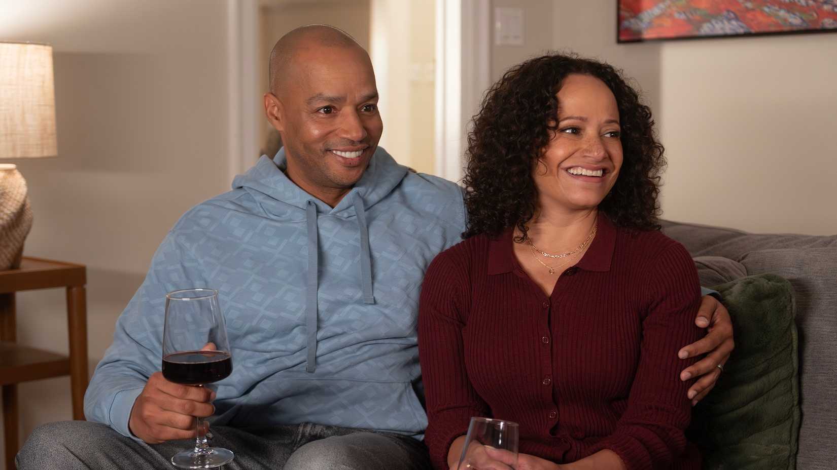Turk and Carla sitting on the couch together, each holding a glass of wine