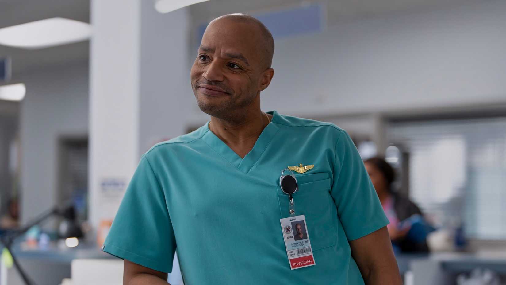 Turk smirking while dressed in his green surgical scrubs