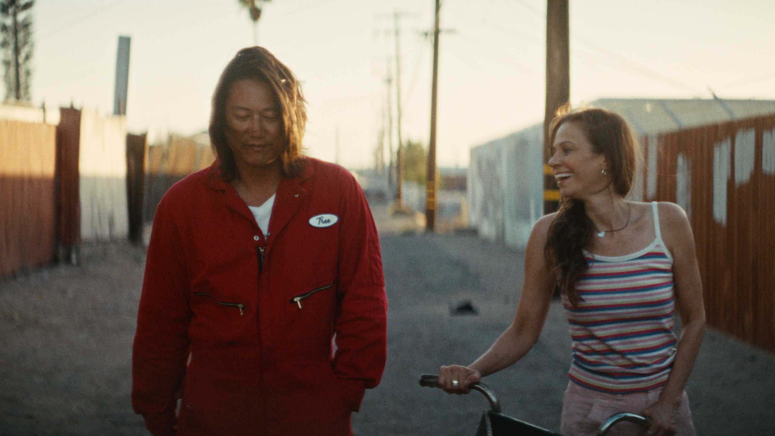 Sung Kang and a woman with a bicycle walking together and smiling in Drifter