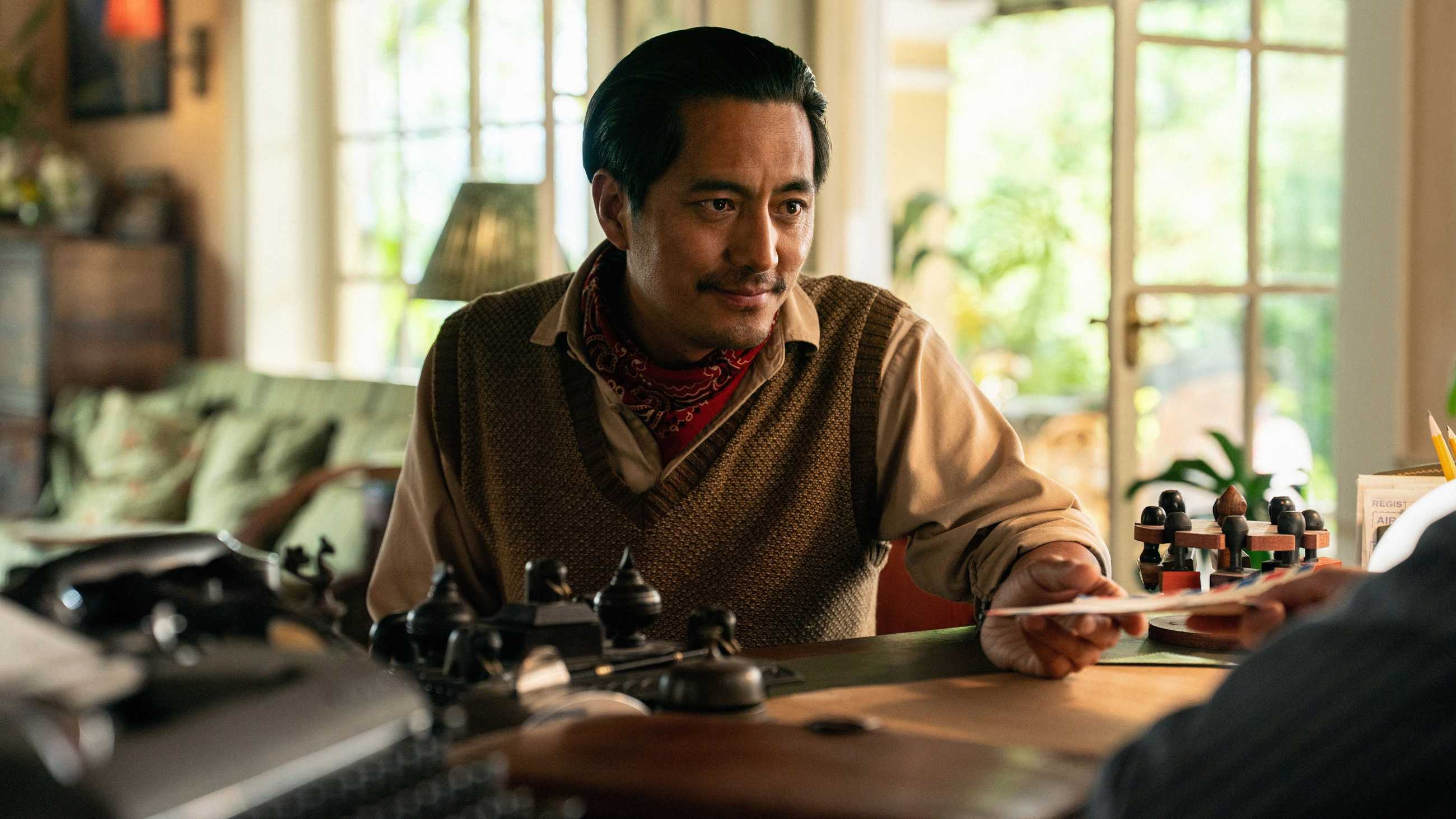 Tenzing Norgay smiling as he's handed an envelope in Tenzing