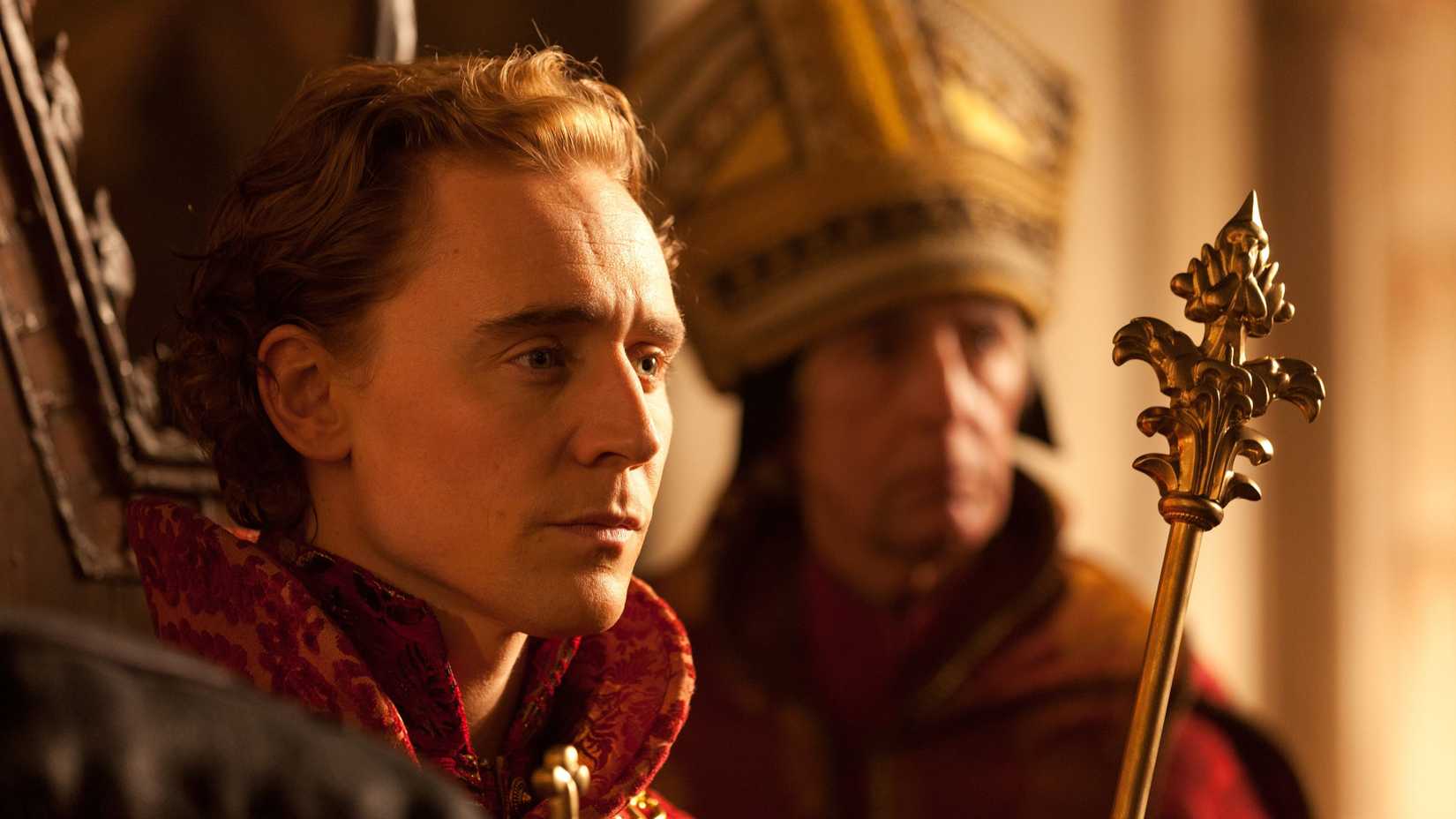 Tom Hiddleston as Henry V sitting on his throne in The Hollow Crown.