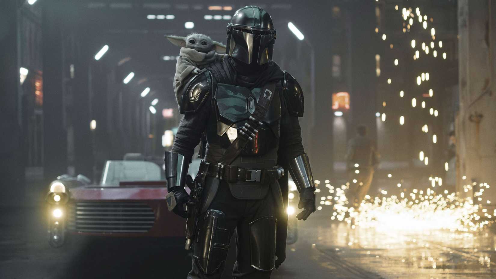 The Mandalorian with Grogu on his shoulder and sparks behind them in The Mandalorian and Grogu