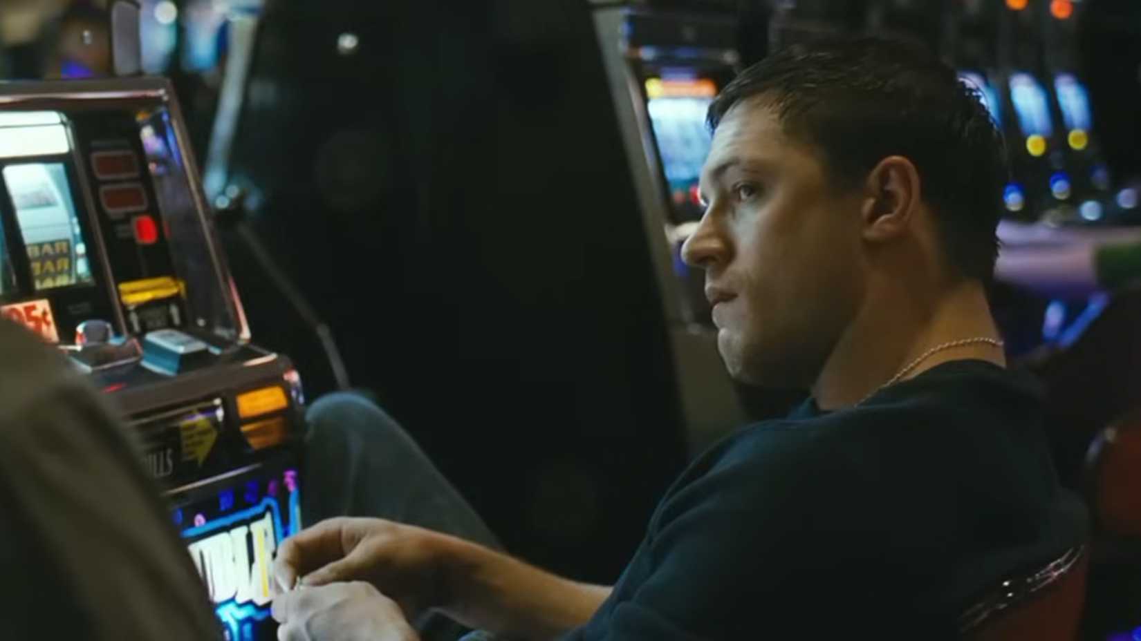 Tom Hardy sitting next to a slot machine in Warrior