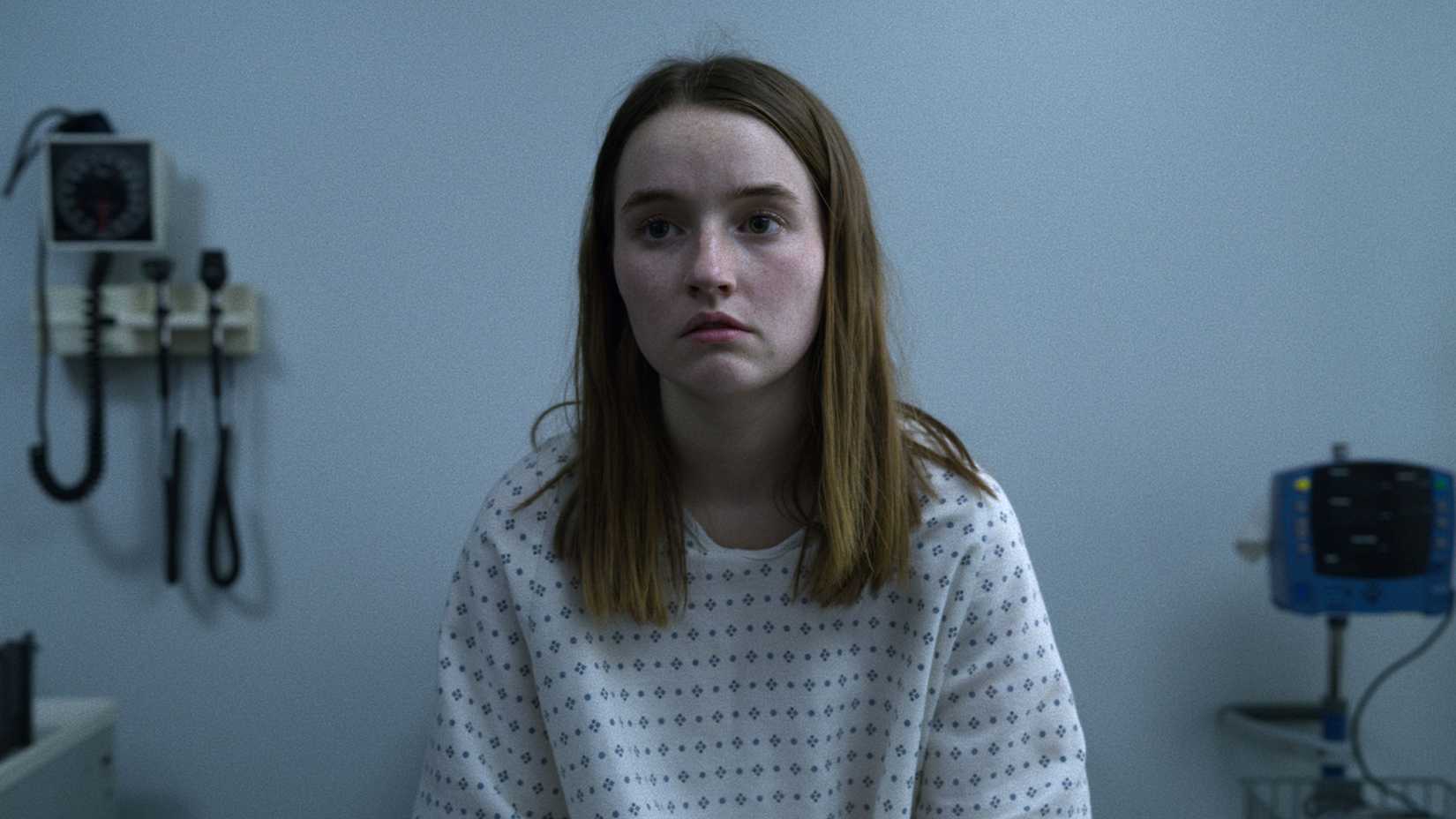 Kaitlyn Dever as Marie Adler sitting in a hospital room in a gown in Unbelievable.