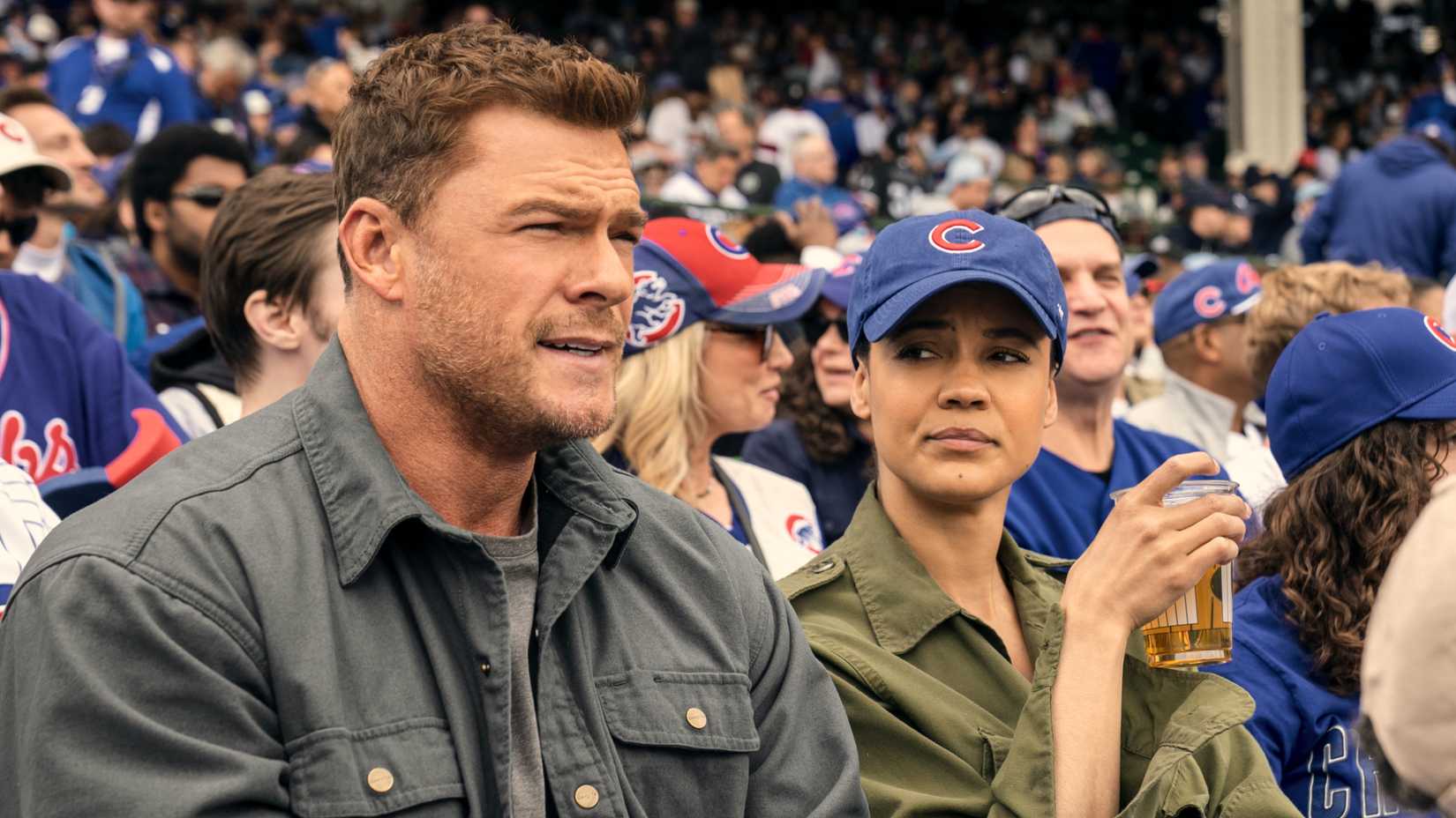 Alan Ritchson Reacher and Maria Sten’s Neagley sitting in a stadium in Neagley season 1
