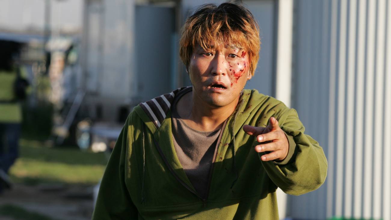 A bloodied Song Kang-ho pointing in shock in front of him in The Host