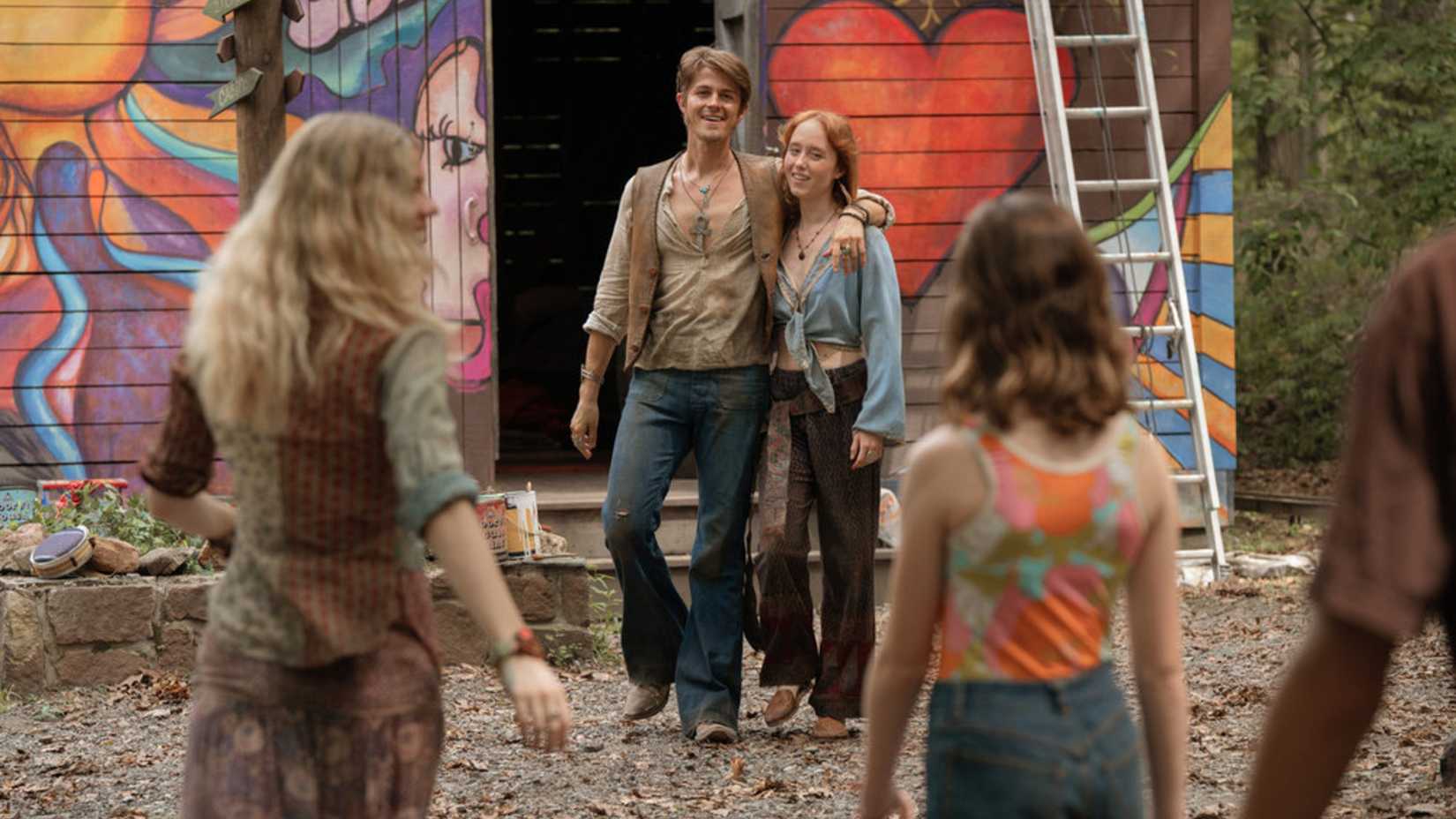 A group of hippies is outside a painted cabin in Crystal Lake