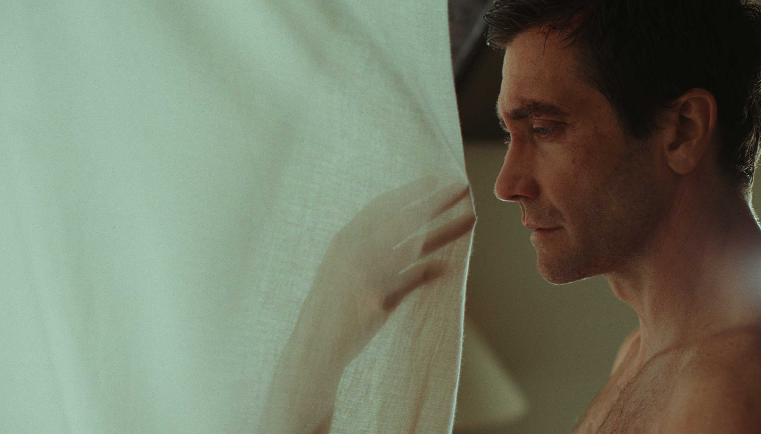 A hand reaching through a sheet at Jake Gyllenhaal in Remain