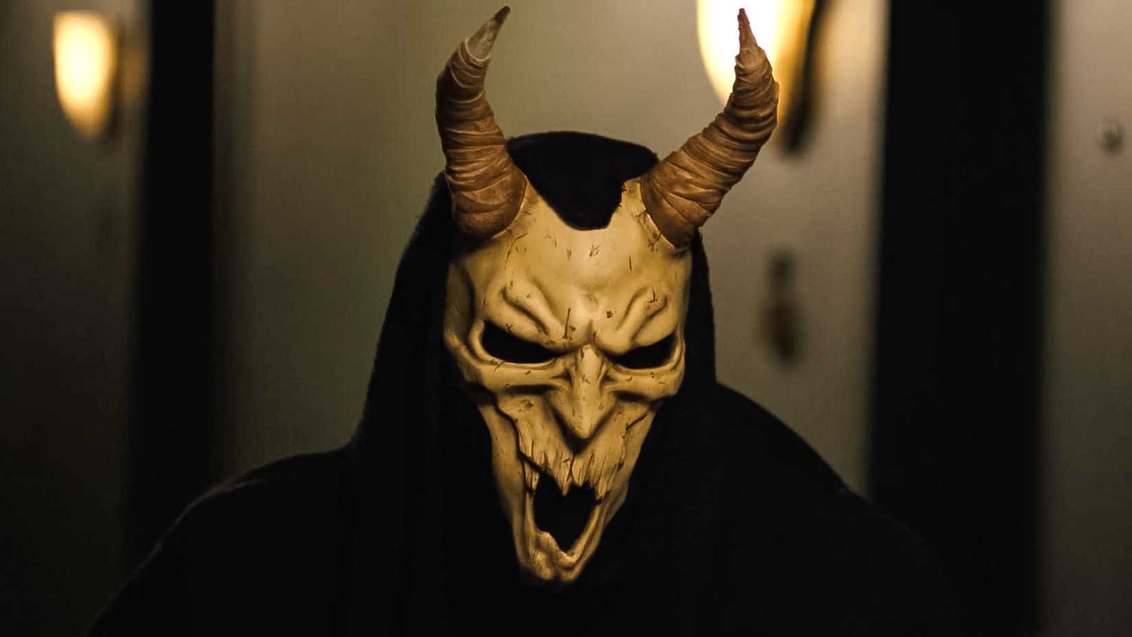 The Baphomet Killer wears a terrifying mask with horns and a black cloak in Shudder's Hell Motel