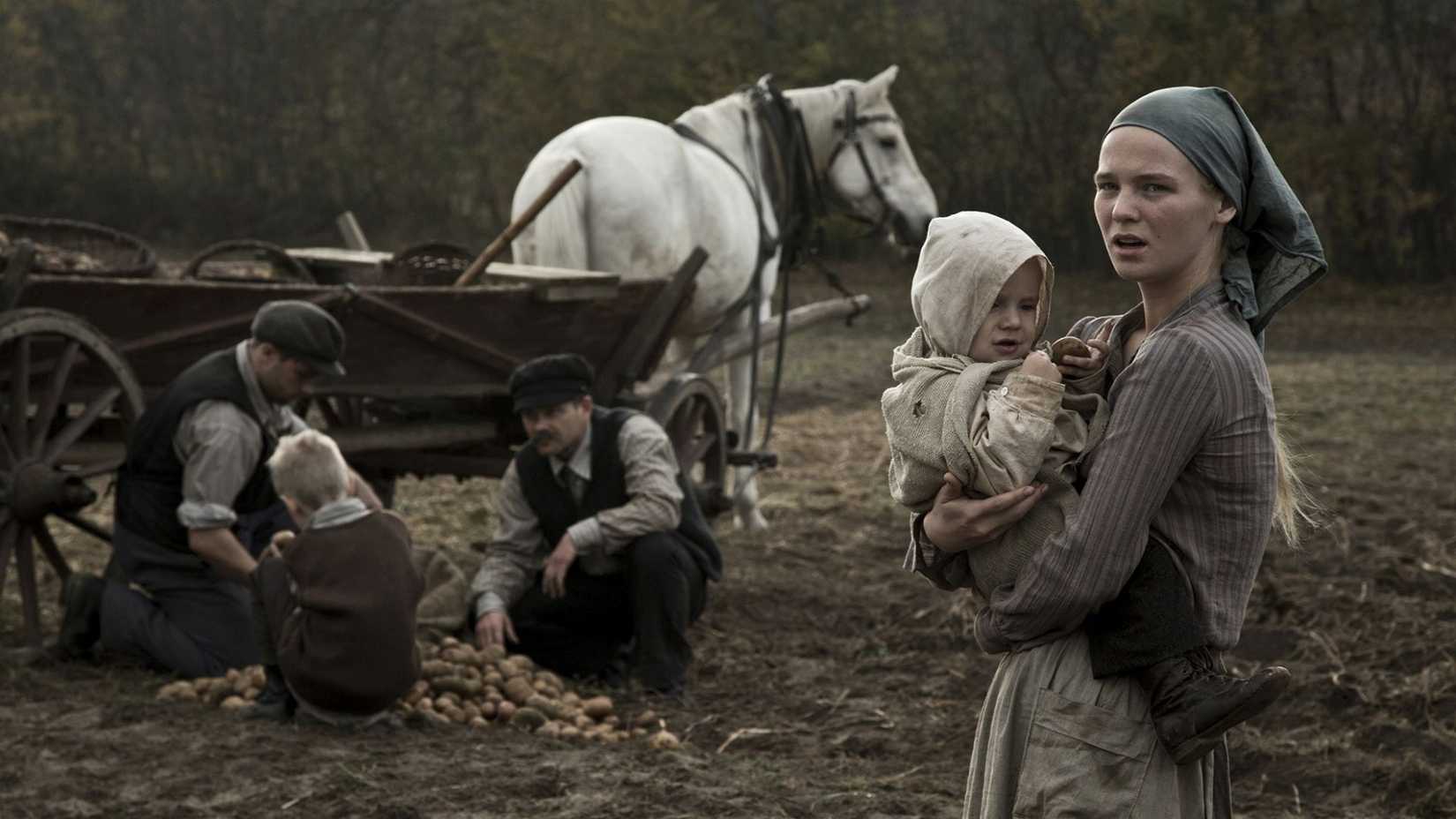 A woman holding a child in a field in Hatred (2016)