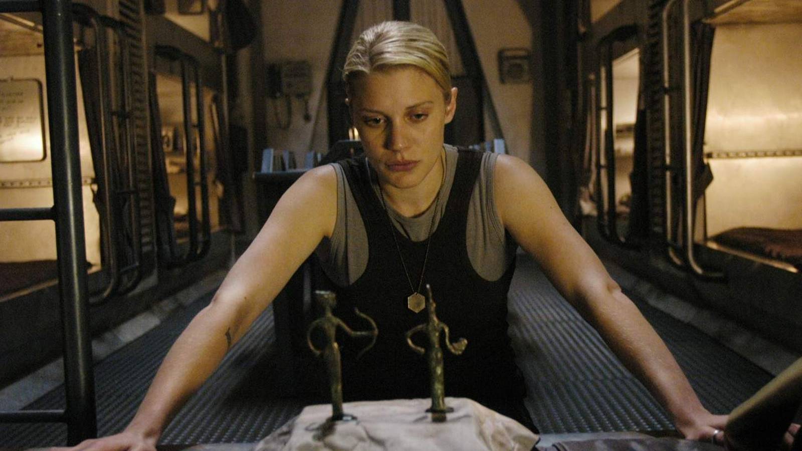 Kara leaning against a table with figures on it in Battlestar Galactica 