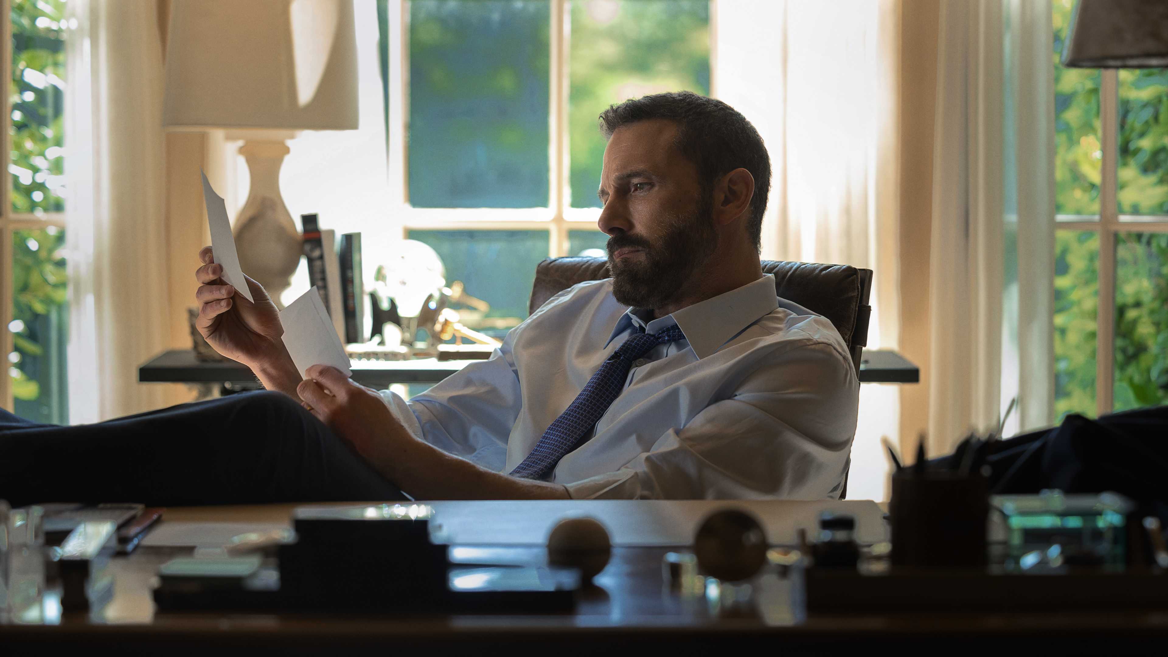 Ben Affleck looking at photos at his desk in Animals