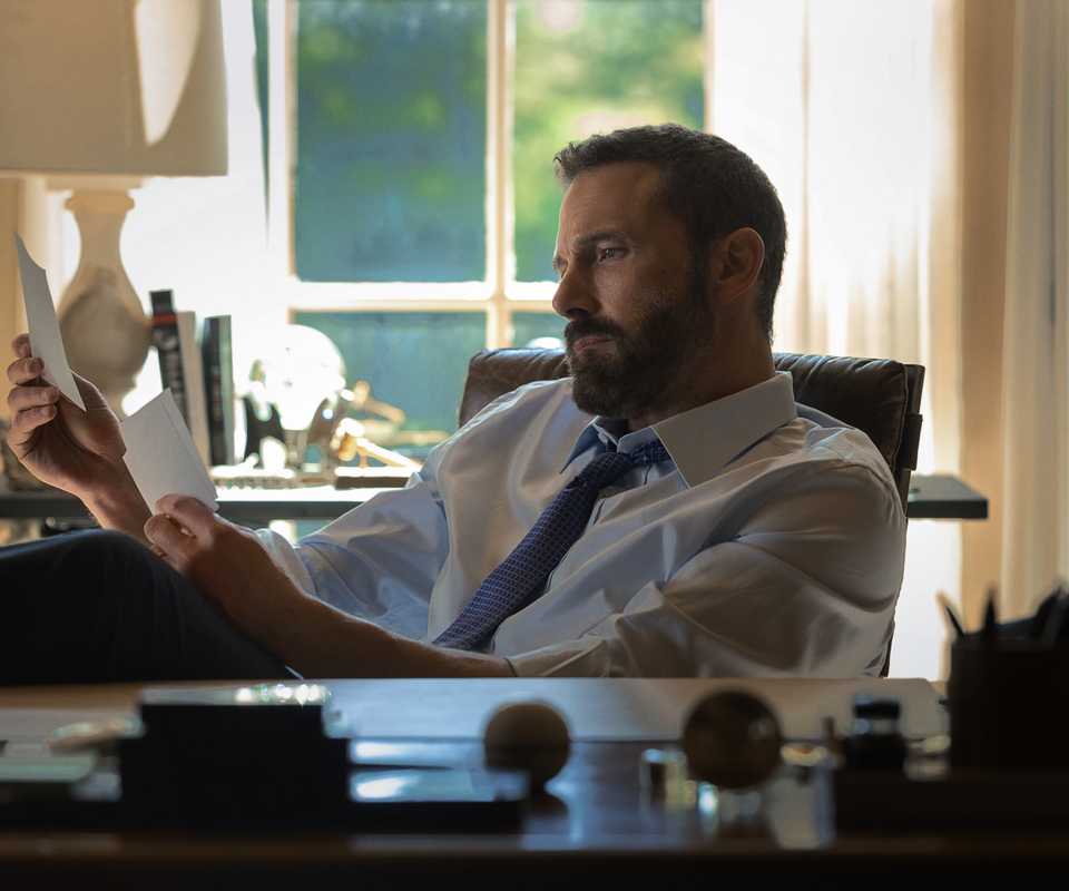 Ben Affleck looking at photos at his desk in Animals