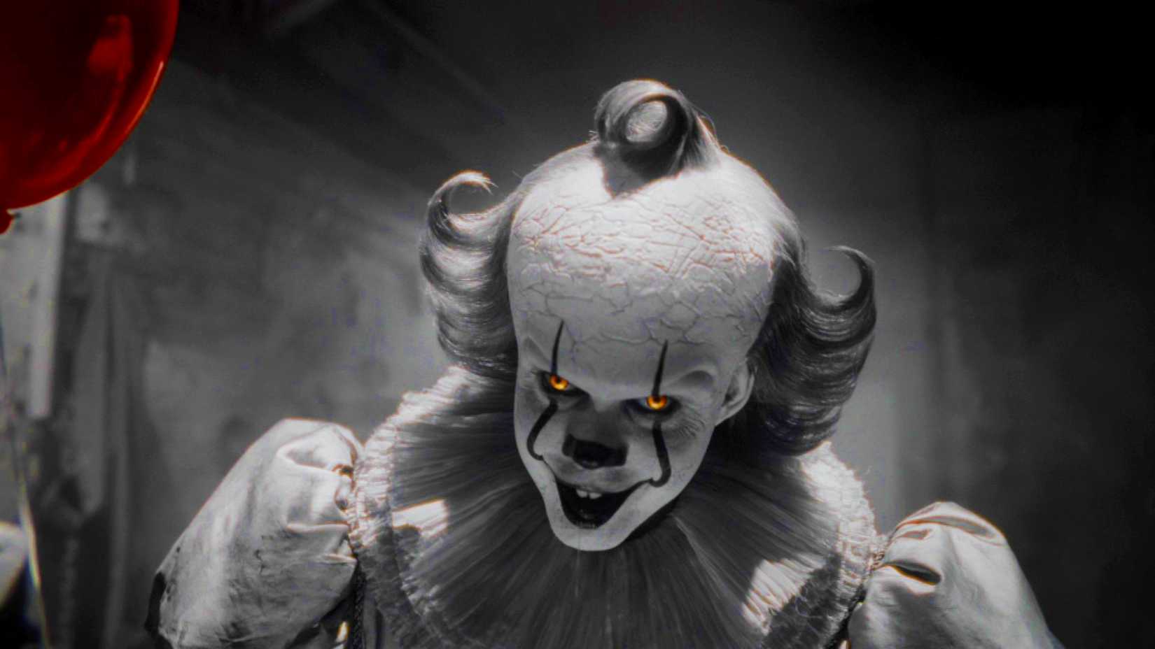 Bill Skarsgard as Pennywise holding a balloon and smiling in black and white in It Welcome to Derry season 1