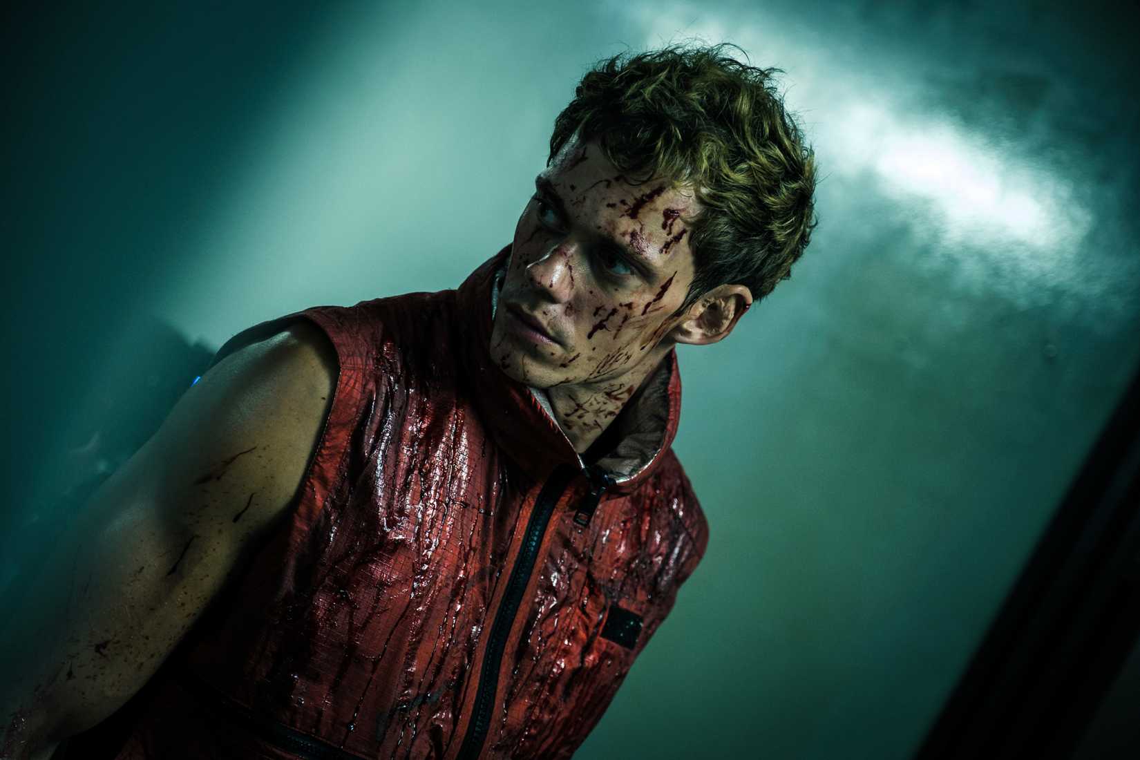 Bill Skarsgaard stands covered in blood and looks intensely off camera in Boy Kills World.