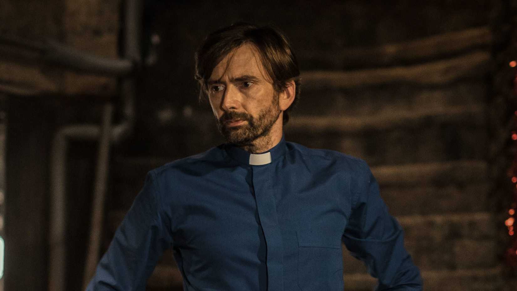 David Tennant looks to the side upset while in the basement of Inside Man