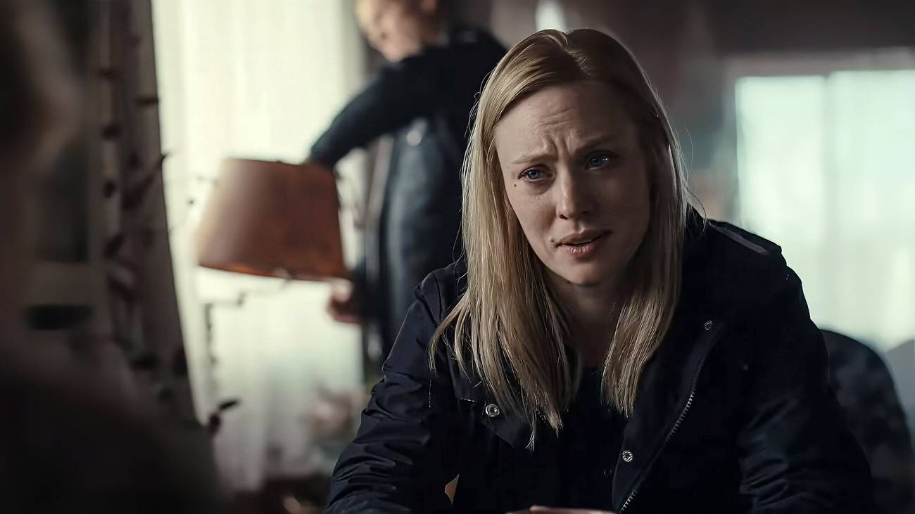 Deborah Ann Woll talking to someone as a cop fixes a lamp behind her in The Cycle