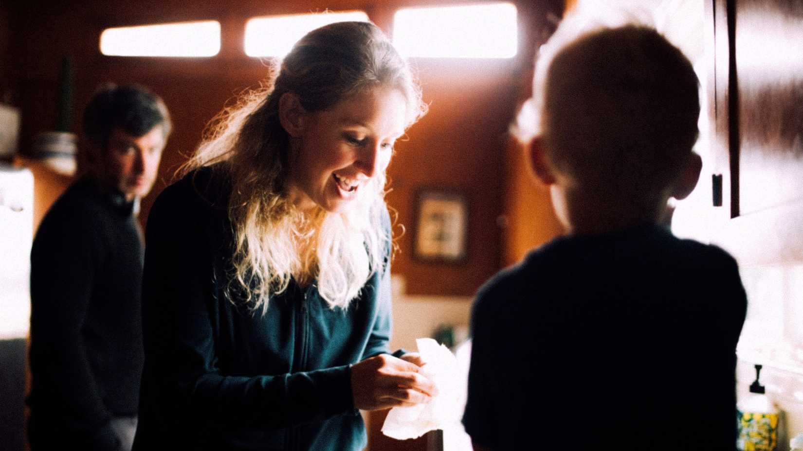 Elizabeth Holmes interacting with a child as Nathan Fielder watches in You Can See Everything