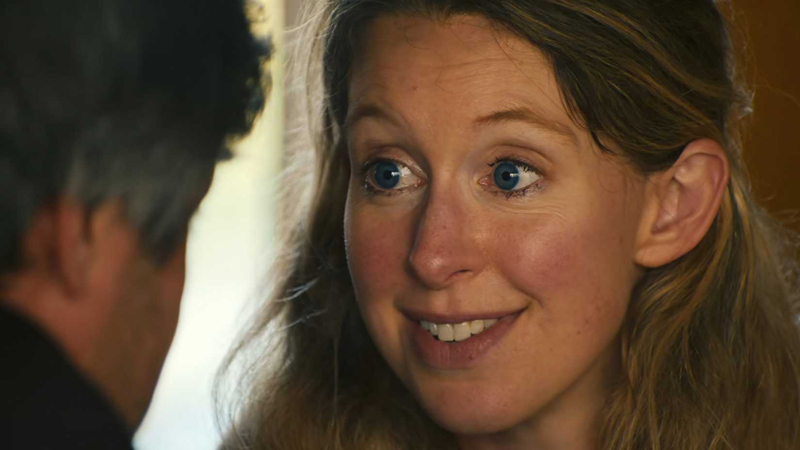 Elizabeth Holmes smiling and staring into Nathan Fielder's eyes in You Can See Everything