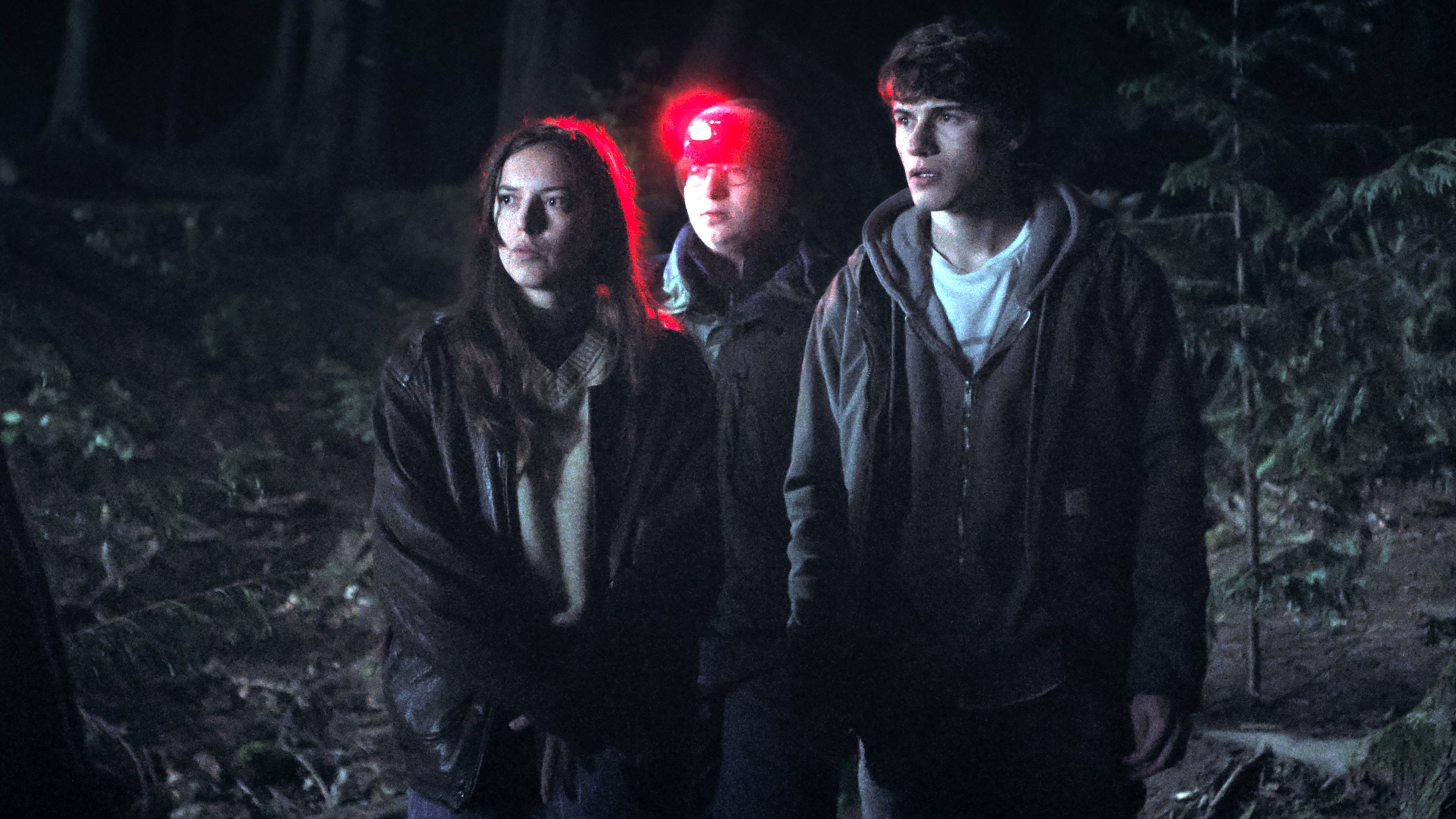 grace-brennan-s-mallory-colter-lee-s-weldon-and-sam-nivola-s-sonny-looking-suspiciously-while-standing-in-a-forest-at-night-in-phony Phony: Hulu’s New Mystery Series Is An Instantly Gripping & Enjoyable Ride | Review