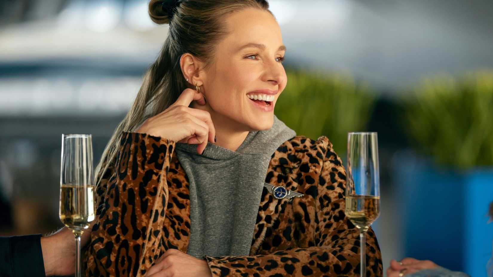 Joanne Williams (Kristen Bell) smiling in a leopard coat and grey hoodie in Nobody Wants This season 3