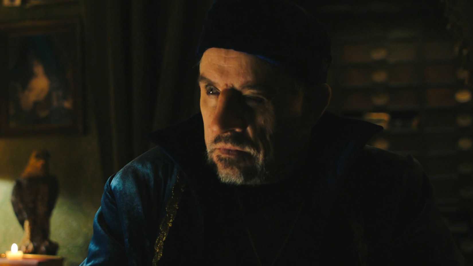 Mark Hamill's Damon Nostra looking intently at someone in his parlor in Carrie